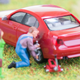 A toy man changes a tire on a model car